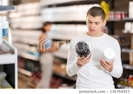 Guy chooses protein sports nutrition in store 136768955