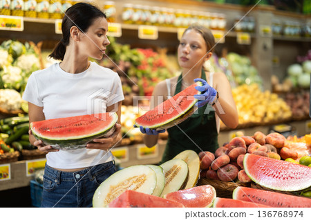 Adult woman chooses watermelon with help of saleswoman 136768974