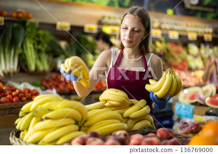 Woman seller putting bananas on the counter 136769000