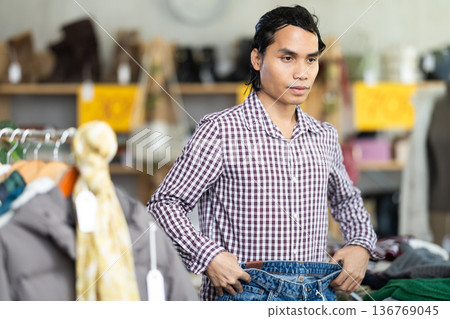 In chain shop, Indonesian man choose jeans In chain shop, Indonesian man choose jeans 136769045