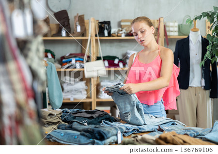 Teenage girl choosing pantaloons in clothing store Teenage girl choosing pantaloons in clothing store 136769106