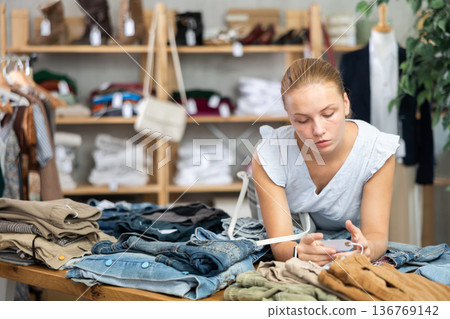 Teenage girl choosing pantalones in store Teenage girl choosing pantalones in store 136769142