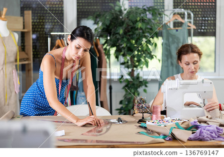 Woman tailor draw dress pattern with curve ruler on paper, female master seamstress sewing Woman tailor draw dress pattern with curve ruler on paper, female master seamstress sewing 136769147