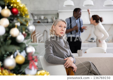 Dissatisfied elderly woman is tired of constant quarrels of married couple during Christmas holiday Dissatisfied elderly woman is tired of constant quarrels of married couple during Christmas holiday 136769150