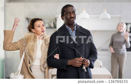 Middle-aged couple leaving the house while old woman quarreling to them Middle-aged couple leaving the house while old woman quarreling to them 136769235