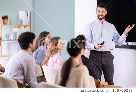 man stands with a remote control in front of students man stands with a remote control in front of students 136769281