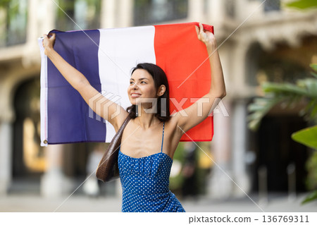 Girl waving France flag on street of summer city Girl waving France flag on street of summer city 136769311