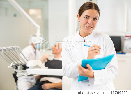 Young woman nurse with paper is standing in dental office, clinic 136769321