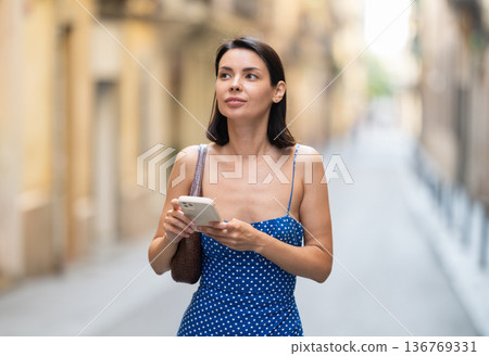Young woman with mobile phone on city street Young woman with mobile phone on city street 136769331