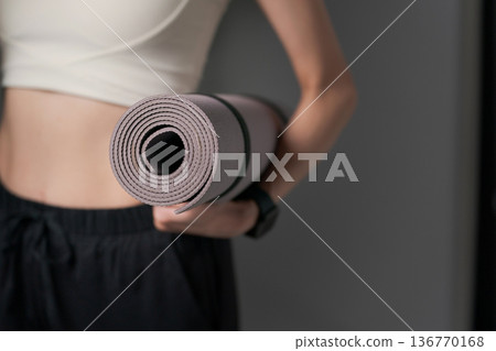 畫面中一名女子手持瑜珈墊。 136770168