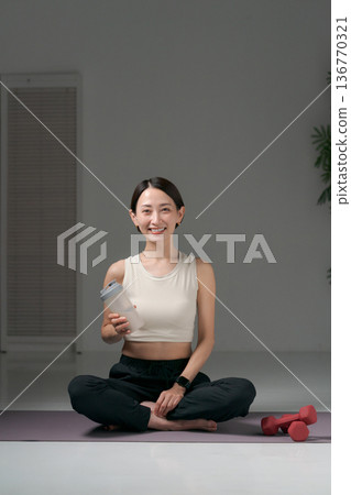 一位身穿運動服和瑜珈服的女士坐著 一位身穿運動服和瑜珈服的女士坐著 136770321