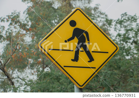 Yellow pedestrian crossing sign with walking figure icon. Road safety warning symbol in outdoor environment. Traffic sign for crosswalk area and urban transportation concept. Yellow pedestrian crossing sign with walking figure icon. Road safety warning symbol in outdoor environment. Traffic sign for crosswalk area and urban transportation concept. 136770931