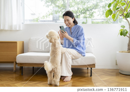 一位中年婦女抱著她的寵物狗和一部智慧型手機。 136771911