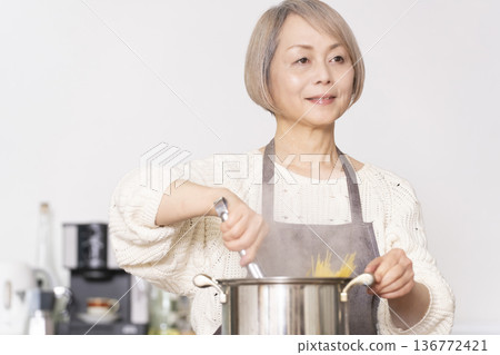Senior woman boiling pasta in the kitchen Senior woman boiling pasta in the kitchen 136772421