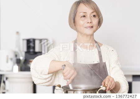 Senior woman boiling pasta in the kitchen Senior woman boiling pasta in the kitchen 136772427