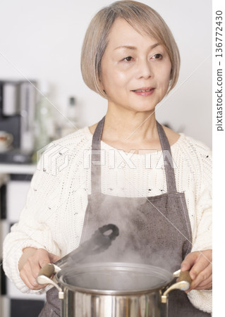 Senior woman boiling pasta in the kitchen 136772430
