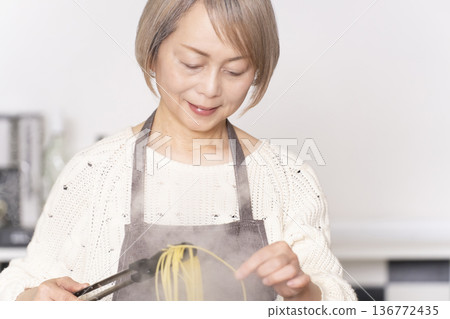Senior woman boiling pasta in the kitchen Senior woman boiling pasta in the kitchen 136772435
