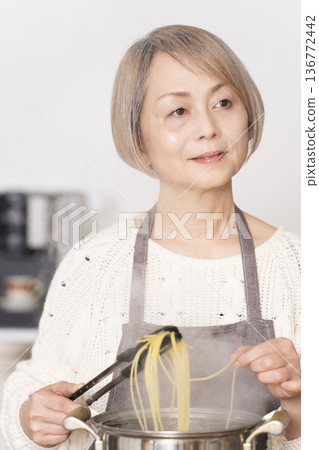 Senior woman boiling pasta in the kitchen 136772442