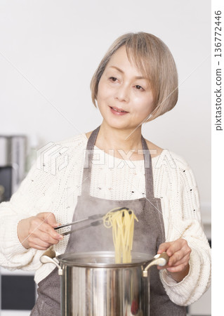 Senior woman boiling pasta in the kitchen Senior woman boiling pasta in the kitchen 136772446