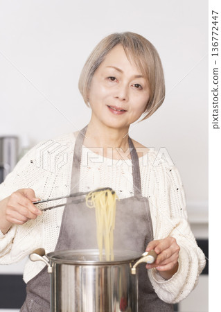 Senior woman boiling pasta in the kitchen Senior woman boiling pasta in the kitchen 136772447