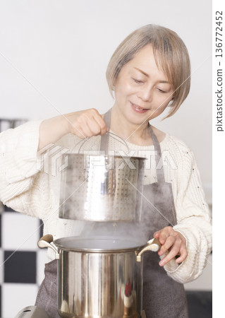 Senior woman boiling pasta in the kitchen 136772452