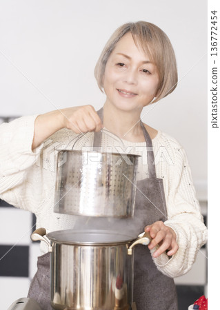 Senior woman boiling pasta in the kitchen Senior woman boiling pasta in the kitchen 136772454