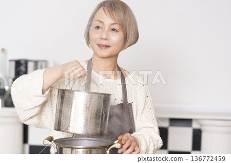 Senior woman boiling pasta in the kitchen Senior woman boiling pasta in the kitchen 136772459