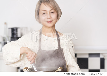 Senior woman boiling pasta in the kitchen 136772473