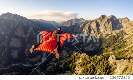 Wingsuit Flyer Soaring High Above Majestic Mountain Range and Valley 136772830