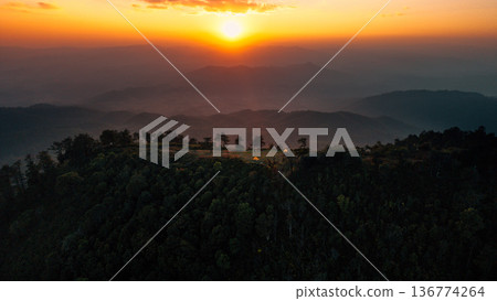 Aerial view of glowing camping tents on a remote mountain ridge at sunset. Aerial view of glowing camping tents on a remote mountain ridge at sunset. 136774264