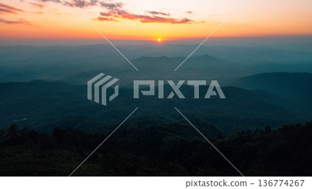 Breathtaking aerial landscape of layered mountains silhouette at golden hour sunset. 136774267
