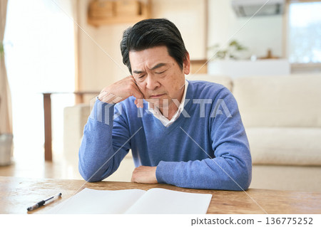 Senior Asian man resting on his elbows in the living room Senior Asian man resting on his elbows in the living room 136775252