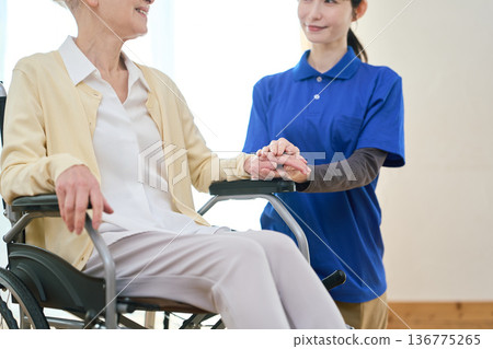 Asian visiting caregiver holding a senior's hand 136775265