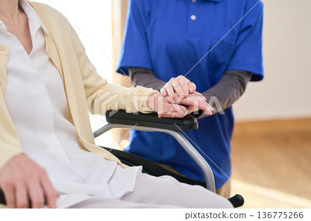 Asian visiting caregiver holding a senior's hand 136775266