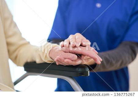 Asian visiting caregiver holding a senior's hand 136775267