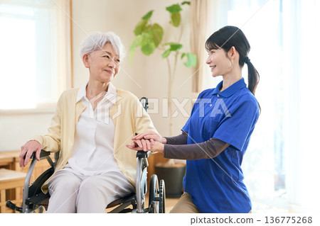 Asian visiting caregiver holding a senior's hand Asian visiting caregiver holding a senior's hand 136775268
