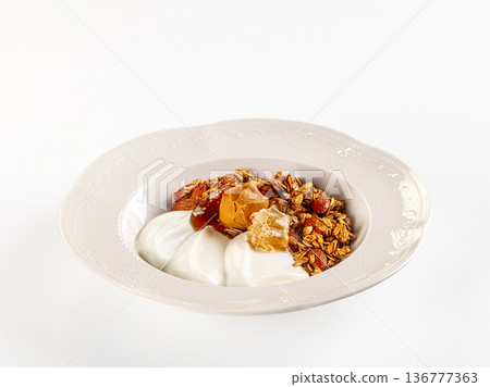 Healthy breakfast yogurt bowl with granola, peanut butter, dates, and fresh honeycomb on a white background. Healthy breakfast yogurt bowl with granola, peanut butter, dates, and fresh honeycomb on a white background. 136777363