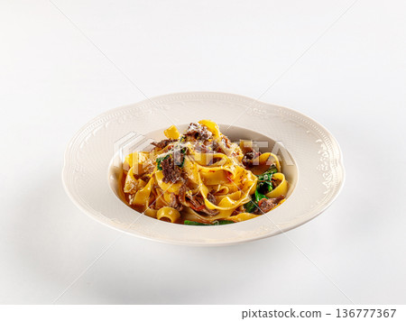 Gourmet fettuccine pasta with beef ragu and spinach, served in an ornate bowl on a white background Gourmet fettuccine pasta with beef ragu and spinach, served in an ornate bowl on a white background 136777367
