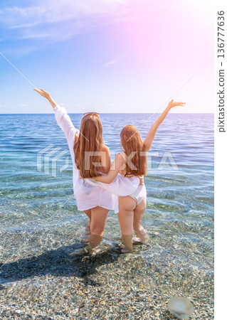 Beach friends summer celebrating freedom while standing in crystal clear sea water under bright sun during vacation 136777636
