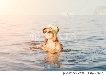 Woman Sunglasses Hat Sea - A woman wearing sunglasses and a hat swims in the sea on a sunny day. Woman Sunglasses Hat Sea - A woman wearing sunglasses and a hat swims in the sea on a sunny day. 136777644
