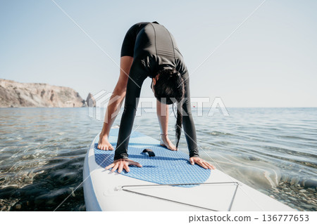 Yoga Paddleboard Woman Water: Woman practicing yoga on a paddleboard in the water. Yoga Paddleboard Woman Water: Woman practicing yoga on a paddleboard in the water. 136777653