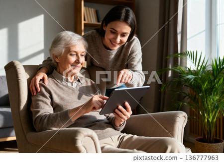 Elderly caucasian woman using tablet with young caucasian female assistance 136777963