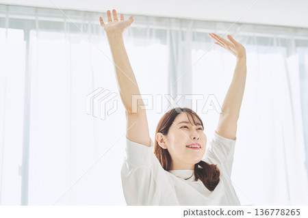 A woman taking a deep breath and relaxing in natural morning light A woman taking a deep breath and relaxing in natural morning light 136778265