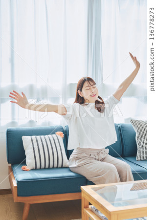 A woman taking a deep breath and relaxing in natural morning light A woman taking a deep breath and relaxing in natural morning light 136778273