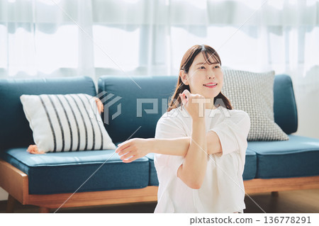 A woman taking a deep breath and relaxing in natural morning light A woman taking a deep breath and relaxing in natural morning light 136778291