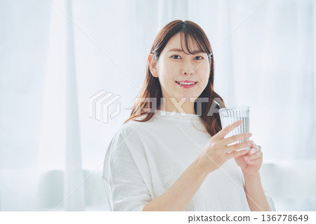 一位女性透過早晨補充水分來維持健康的生活方式。 一位女性透過早晨補充水分來維持健康的生活方式。 136778649