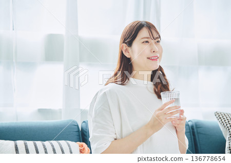 一位女性在放鬆時喝水的日常生活 一位女性在放鬆時喝水的日常生活 136778654