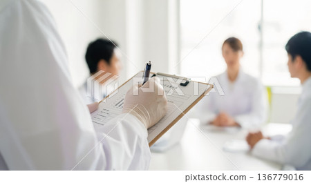 體檢場景,一位日本醫生正在核對體檢問卷的詳細資料。 體檢場景,一位日本醫生正在核對體檢問卷的詳細資料。 136779016