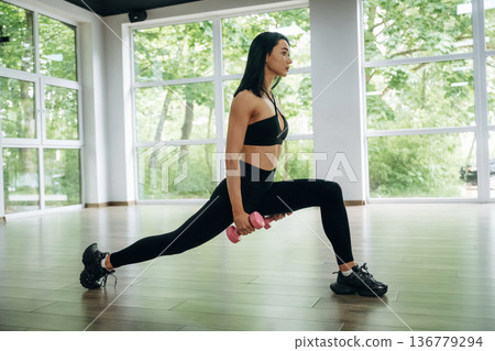 Squats with dumbbells. Woman is doing fitness indoors Squats with dumbbells. Woman is doing fitness indoors 136779294