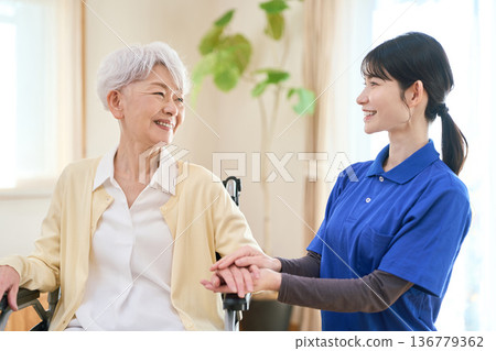 Asian visiting caregiver holding a senior's hand 136779362